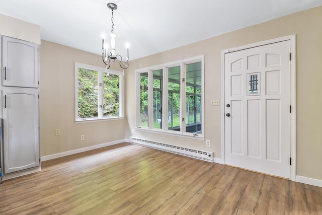 unfurnished dining area featuring light hardwood / wood-style flooring, a chandelier, and a baseboard heating unit