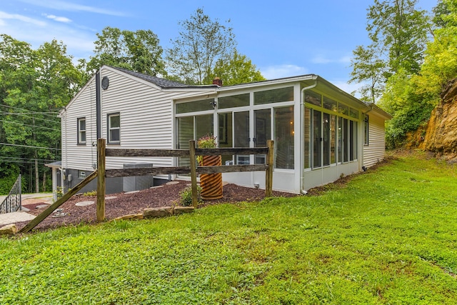 rear view of property featuring a yard and a sunroom