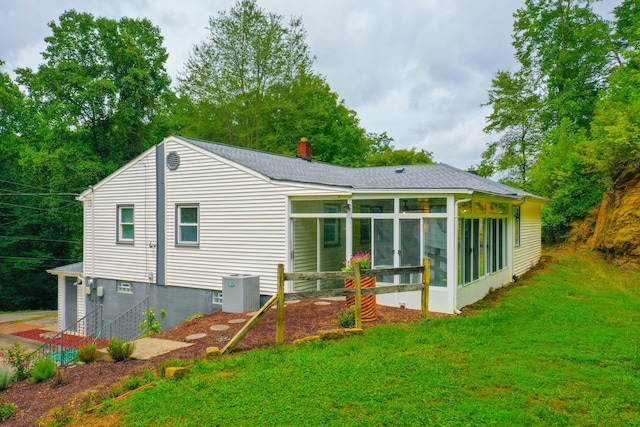 rear view of property with cooling unit, a yard, and a sunroom