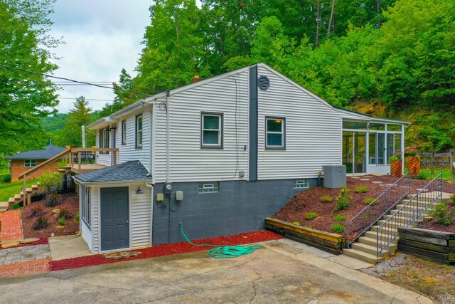 exterior space with central air condition unit, a sunroom, and a patio area