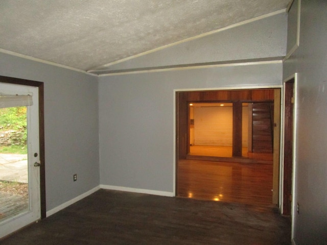 empty room featuring dark wood-type flooring, crown molding, vaulted ceiling, and a textured ceiling