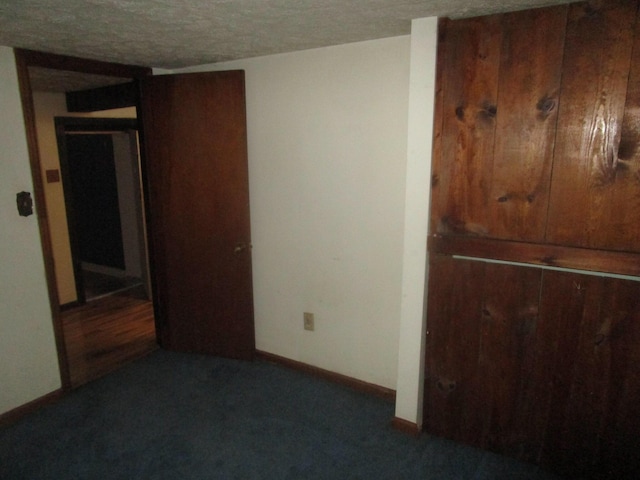 unfurnished bedroom with a textured ceiling and dark colored carpet