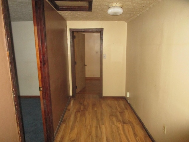 hall with hardwood / wood-style floors and a textured ceiling