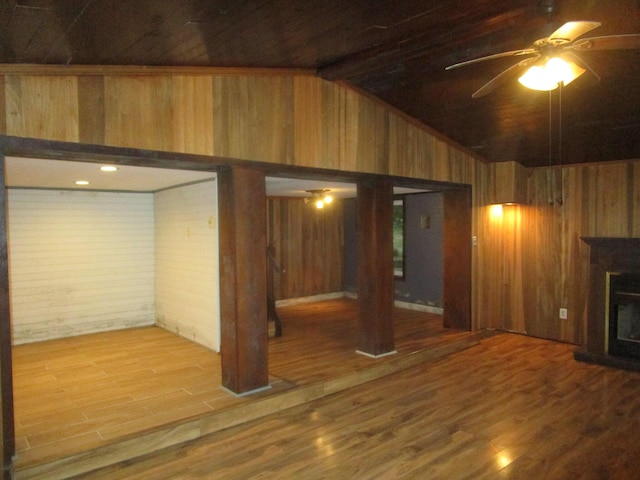 basement featuring ceiling fan, wood-type flooring, and wood walls