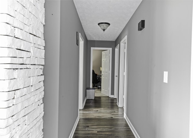 hallway with dark wood-type flooring and a textured ceiling