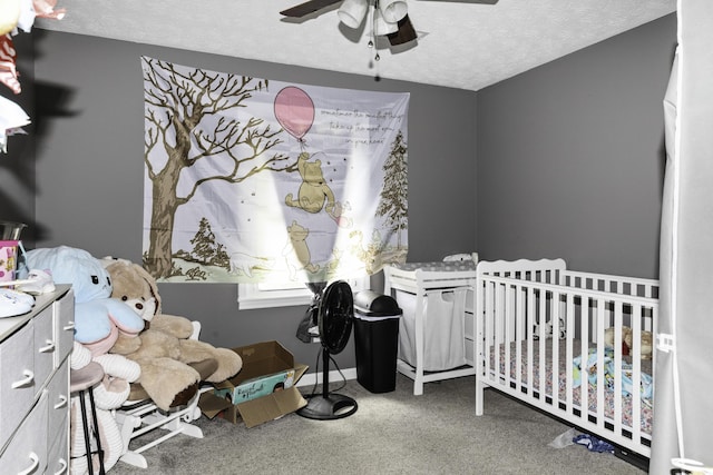 carpeted bedroom with a crib, a textured ceiling, and ceiling fan