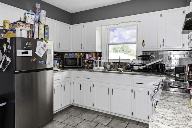 kitchen with sink, backsplash, white cabinets, light stone counters, and stainless steel appliances