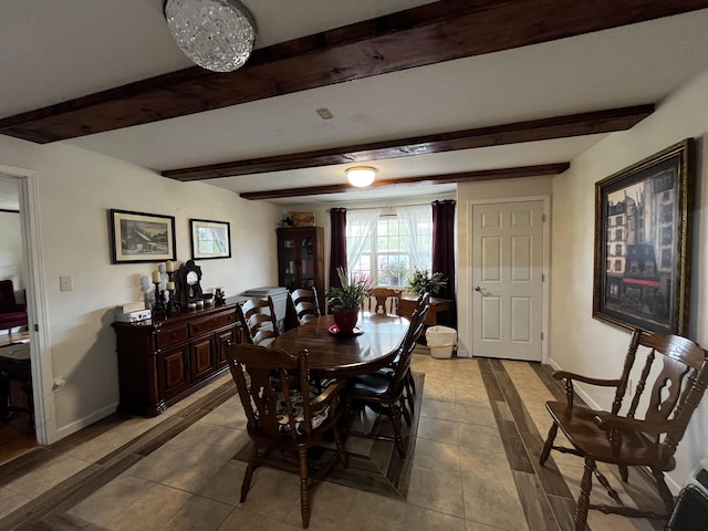 tiled dining space featuring beamed ceiling