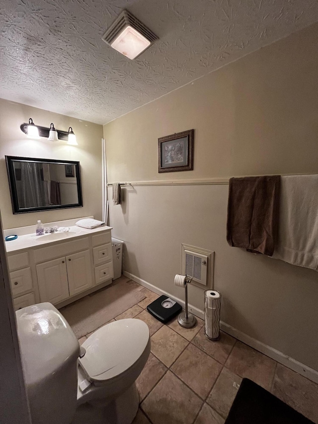 bathroom featuring vanity, tile patterned floors, toilet, and a textured ceiling