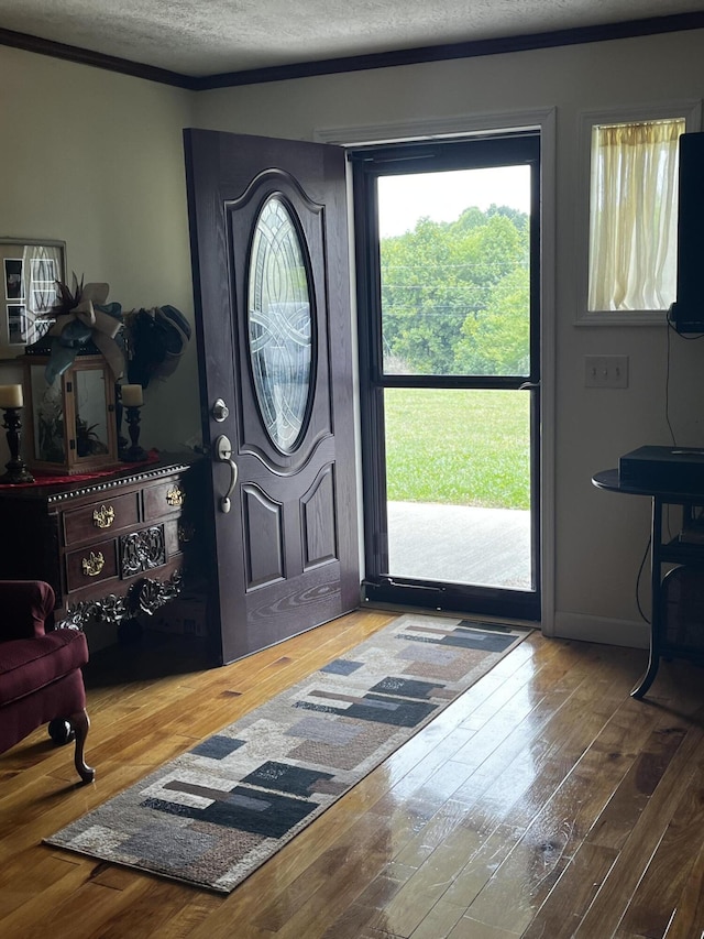 foyer entrance featuring hardwood / wood-style floors, crown molding, and a textured ceiling