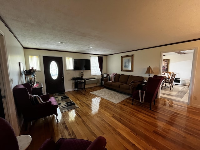 living room with wood-type flooring, a textured ceiling, and crown molding