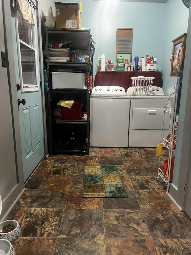 clothes washing area with laundry area, stone finish flooring, and washer and clothes dryer