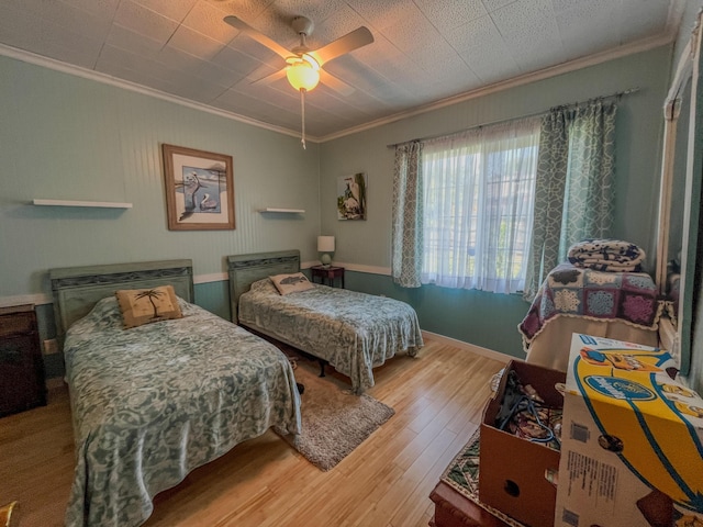 bedroom with ceiling fan, baseboards, crown molding, and wood finished floors