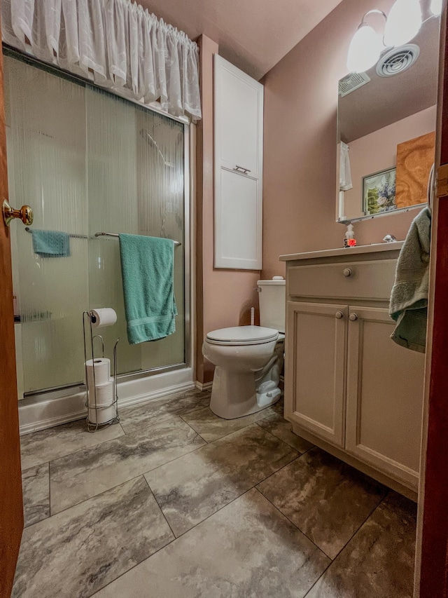 bathroom with toilet, a stall shower, vanity, and visible vents