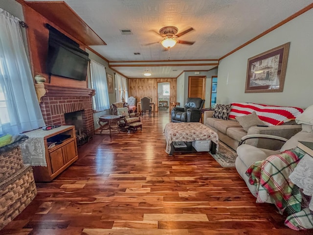 living area with visible vents, ornamental molding, ceiling fan, and wood finished floors