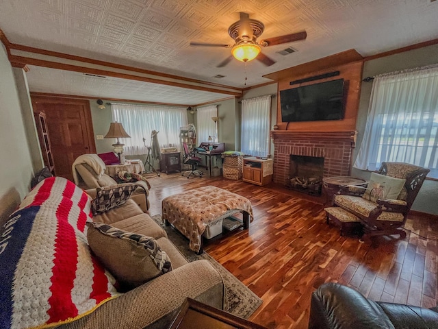 living room with ornamental molding, a brick fireplace, visible vents, ceiling fan, and hardwood / wood-style flooring