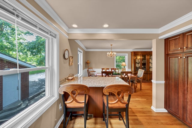 dining room featuring light hardwood / wood-style floors, ornamental molding, and an inviting chandelier