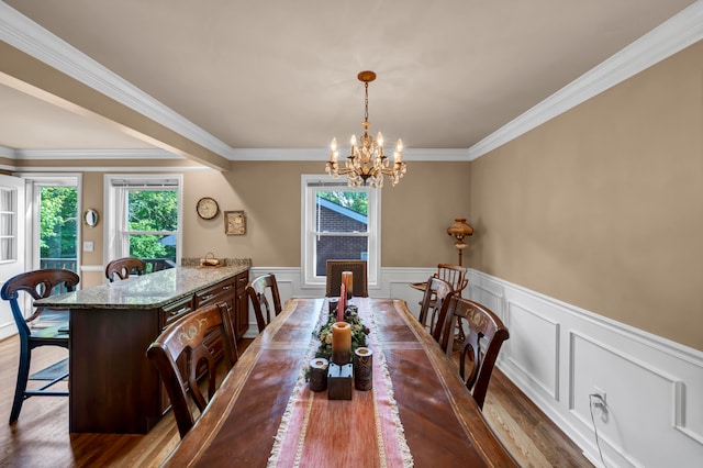 dining space featuring wood-type flooring, crown molding, and a chandelier