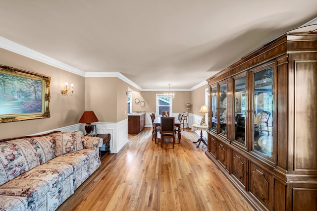 living room featuring light hardwood / wood-style floors, a notable chandelier, and crown molding