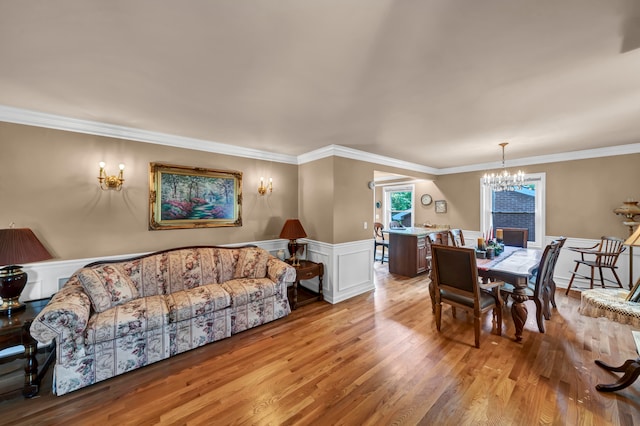 living room with light hardwood / wood-style flooring, ornamental molding, and an inviting chandelier