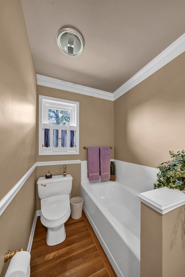 bathroom with crown molding, a washtub, wood-type flooring, and toilet