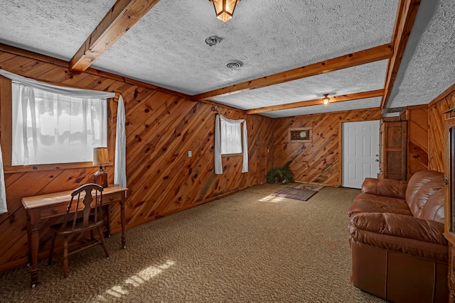 interior space featuring beamed ceiling, carpet floors, a textured ceiling, and wooden walls