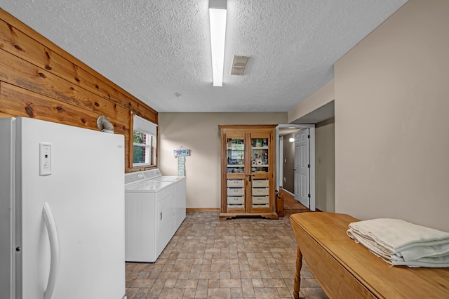 laundry room with washing machine and clothes dryer, a textured ceiling, and light tile patterned floors