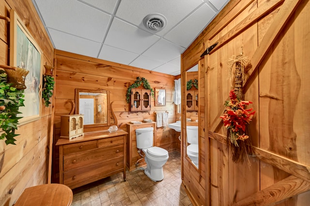 bathroom featuring vanity, tile patterned floors, wooden walls, a paneled ceiling, and toilet