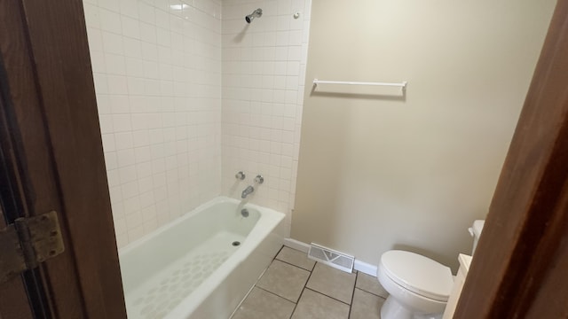 bathroom featuring tiled shower / bath, toilet, and tile patterned flooring