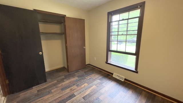 unfurnished bedroom featuring dark wood-type flooring and a closet