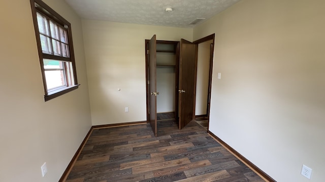 unfurnished bedroom with a closet, dark hardwood / wood-style flooring, and a textured ceiling