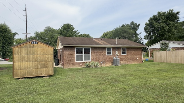 rear view of property with central AC unit, a lawn, and a storage shed