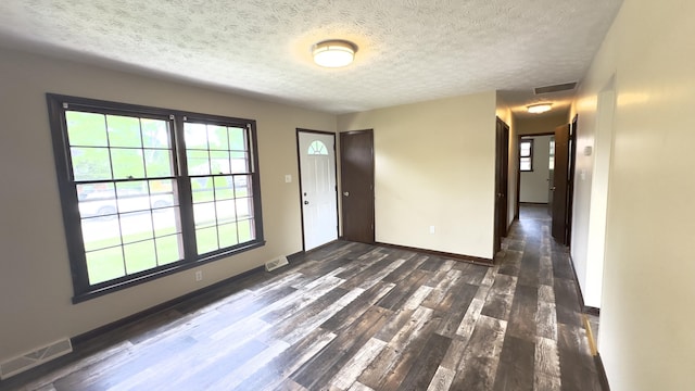 empty room featuring a textured ceiling and dark hardwood / wood-style flooring