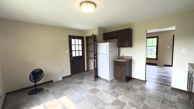 kitchen with dark brown cabinets, a textured ceiling, and white fridge