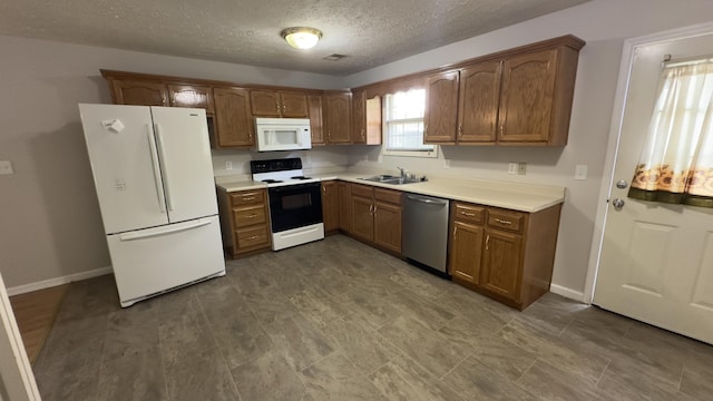 kitchen with baseboards, a sink, white appliances, a textured ceiling, and brown cabinetry