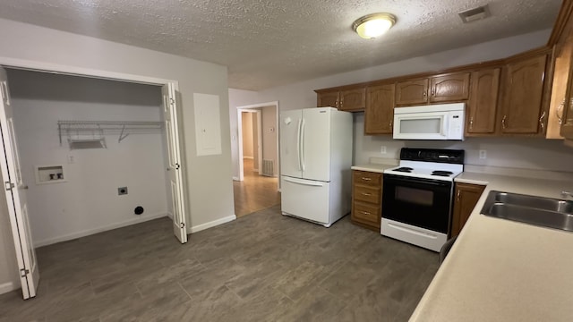 kitchen featuring a textured ceiling, a sink, white appliances, and visible vents