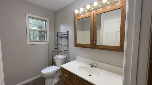 bathroom featuring toilet, vanity, and baseboards