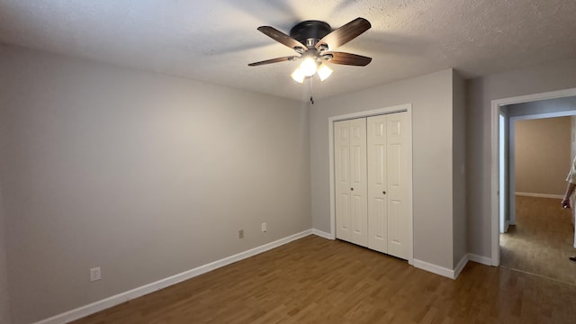 unfurnished bedroom with a ceiling fan, wood finished floors, baseboards, and a closet