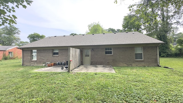 rear view of property featuring roof with shingles, a yard, a patio area, and brick siding