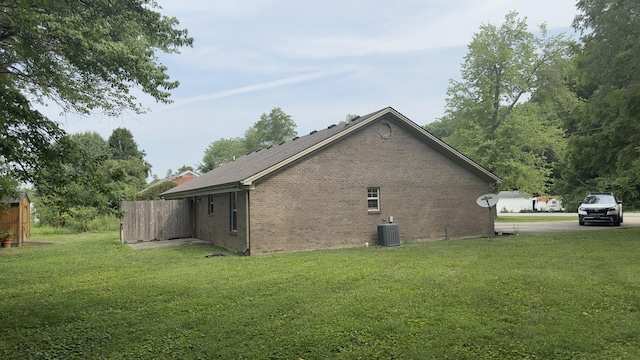 view of side of home featuring brick siding, central air condition unit, and a lawn