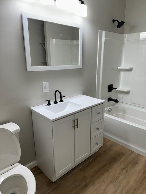 full bathroom with vanity, toilet, wood-type flooring, and shower / tub combination