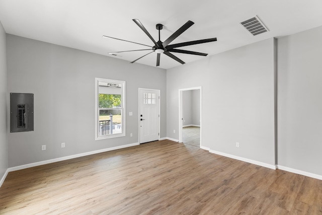 empty room featuring electric panel, light wood-type flooring, and ceiling fan