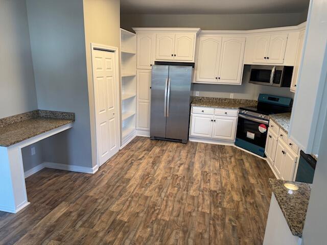 kitchen featuring appliances with stainless steel finishes, dark hardwood / wood-style floors, white cabinetry, and dark stone countertops