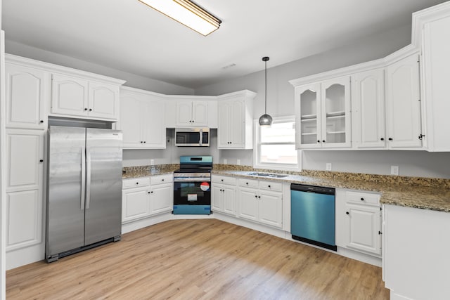 kitchen with white cabinets, appliances with stainless steel finishes, light hardwood / wood-style flooring, and hanging light fixtures