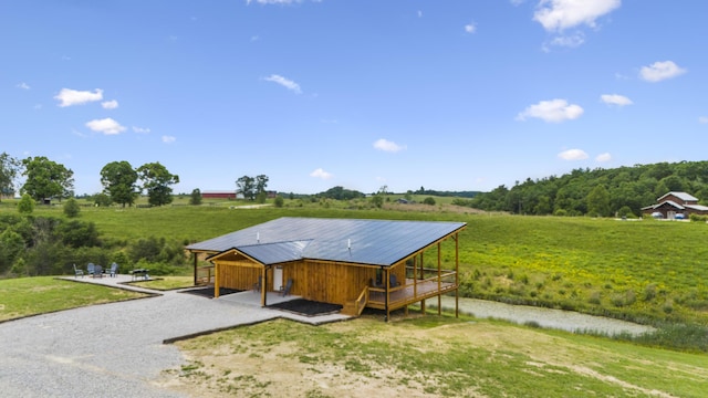 exterior space with a rural view, a deck, and a front yard