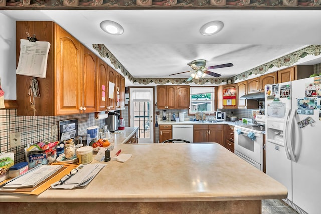 kitchen featuring kitchen peninsula, ceiling fan, tasteful backsplash, and white appliances