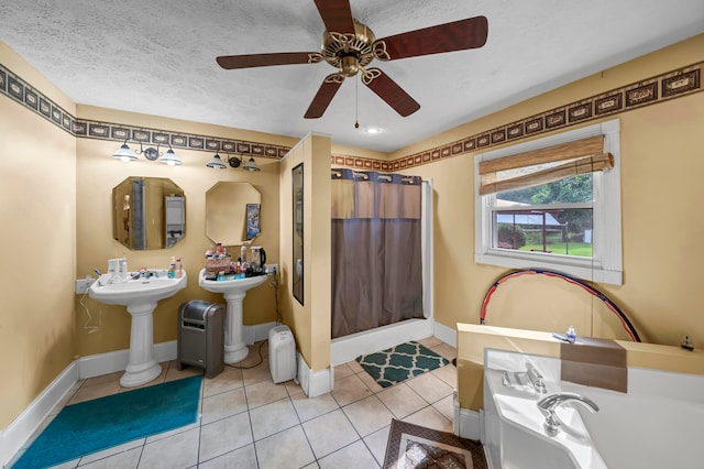 bathroom featuring tile patterned floors, ceiling fan, sink, a bathing tub, and a textured ceiling