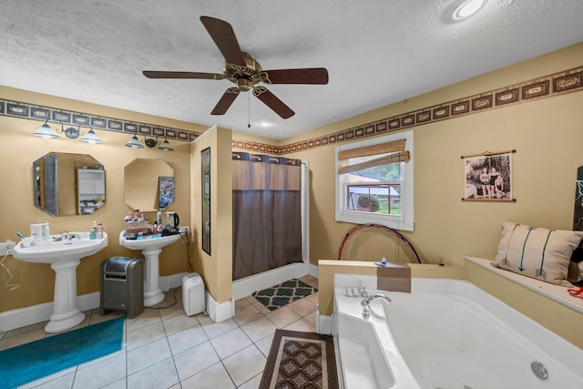 bathroom featuring ceiling fan, a textured ceiling, tile patterned flooring, and a bathtub