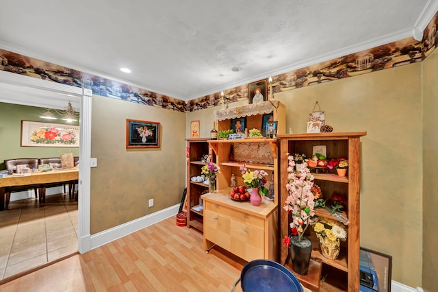 interior space featuring light wood-type flooring, ornamental molding, and a textured ceiling