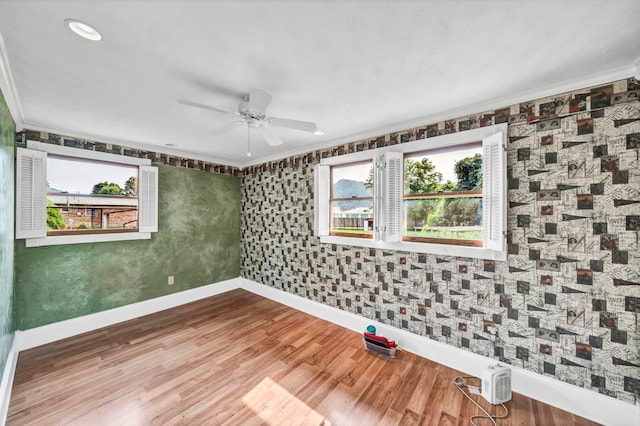 empty room featuring hardwood / wood-style flooring, crown molding, and ceiling fan